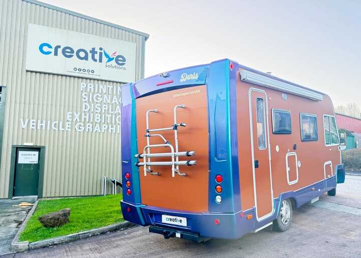 The transformed campervan with its bold copper orange and pearlescent lavender wrap parked outside our Creative Solutions workshop